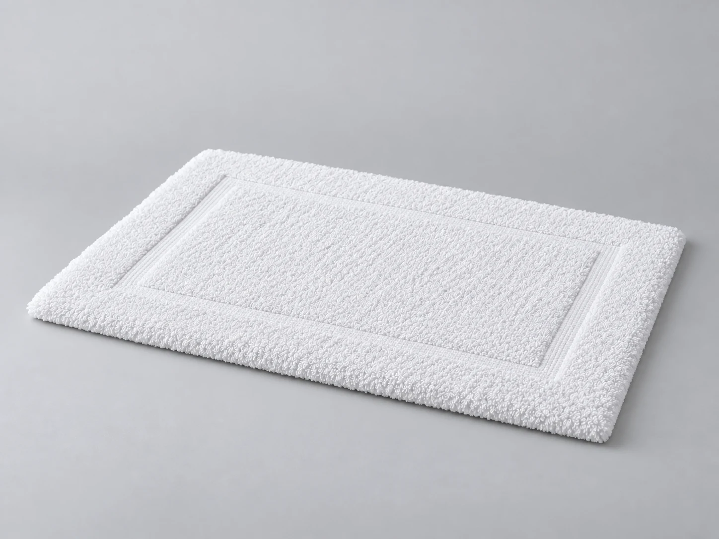 Un tapis de bain blanc sur fond gris doux