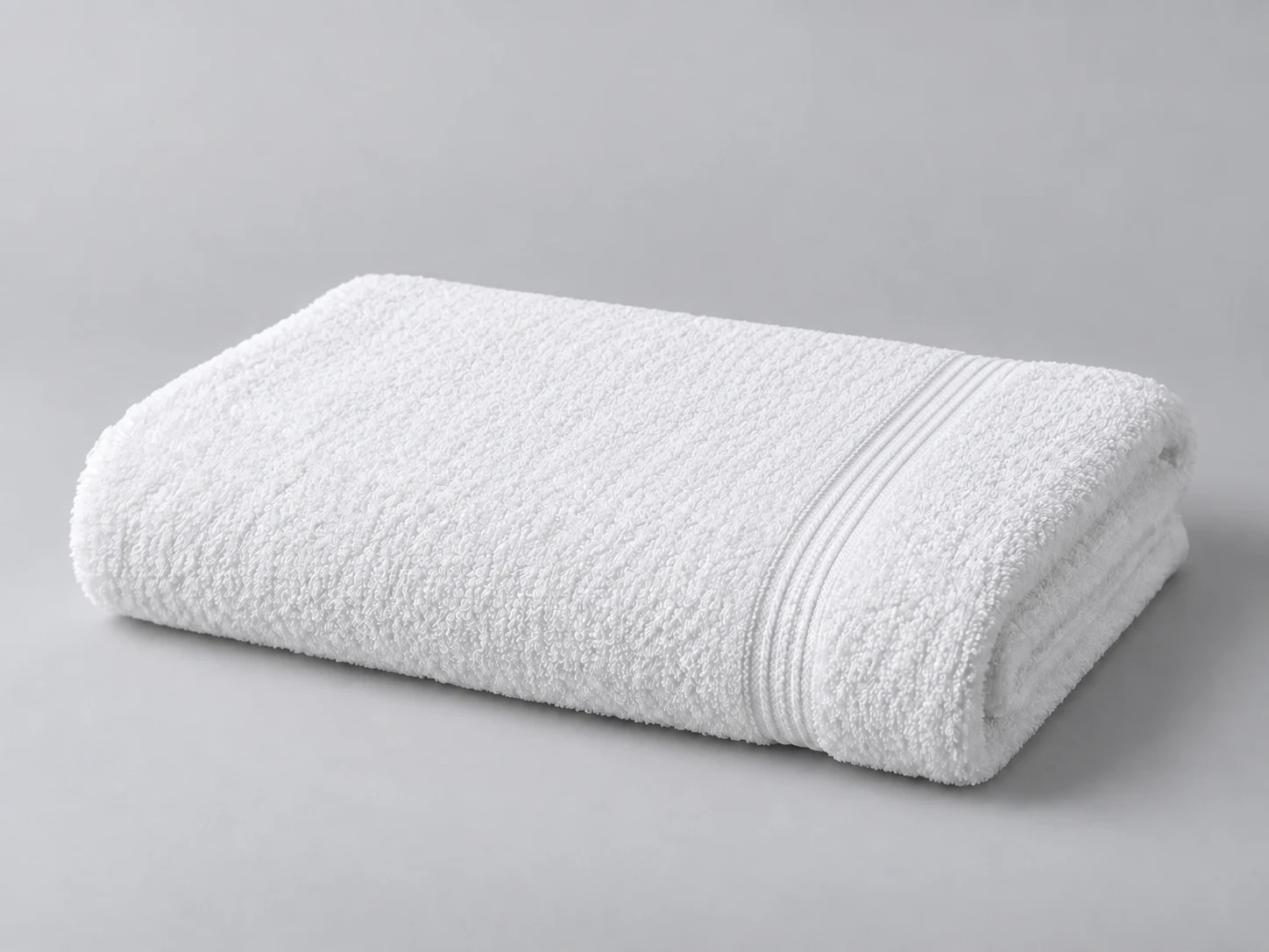 Une serviette de plage blanche pliée sur fond gris doux